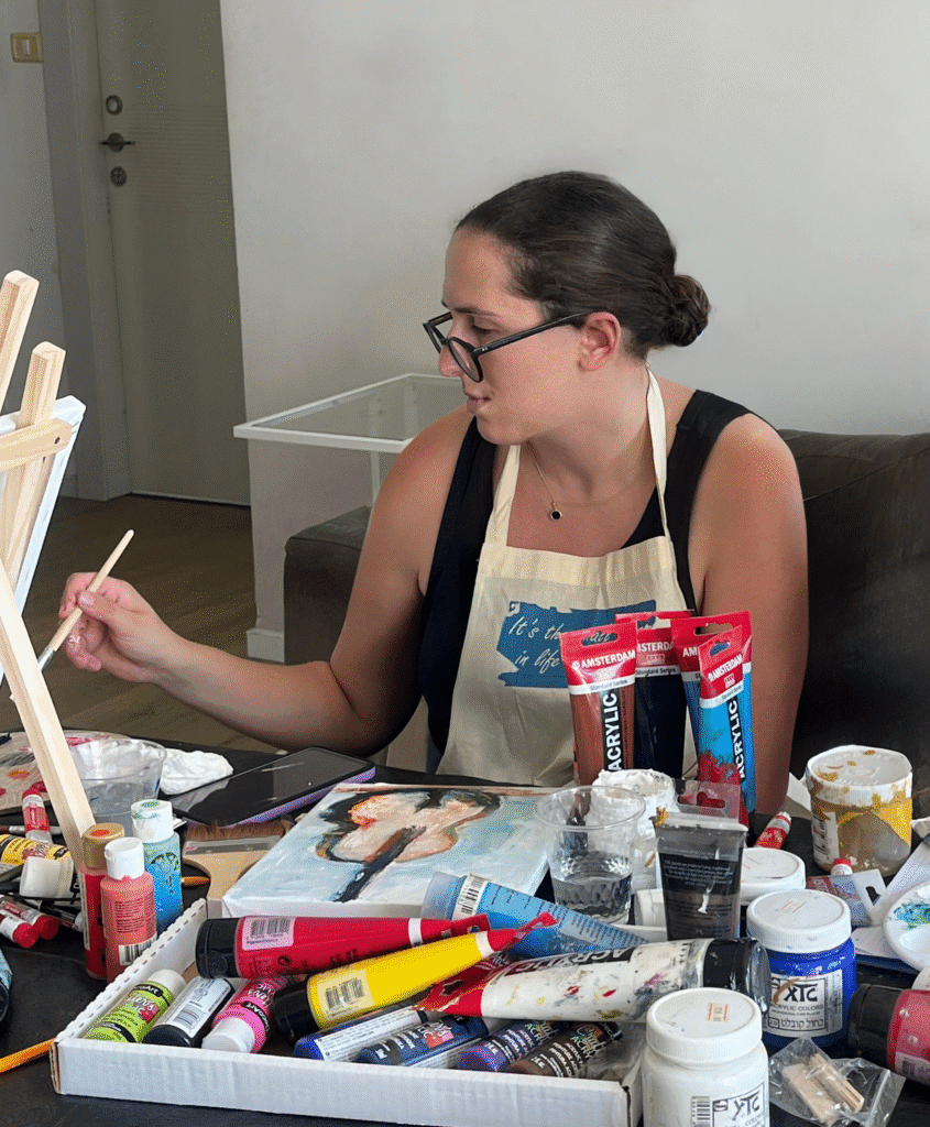 Woman painting with colorful acrylics at a table, art as emotional therapy, embracing creativity and self-reflection.