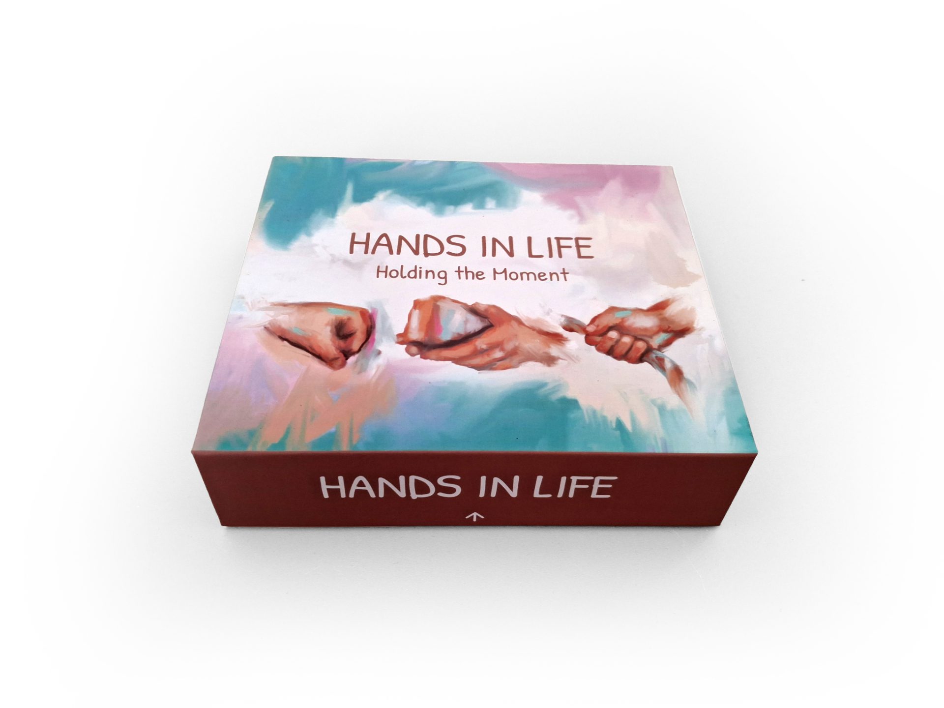 A box of Hands in Life: Holding the Moment therapy cards, illustrating shared connection and creative healing.