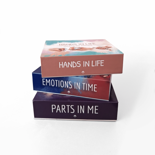 Stack of therapy card sets titled Hands in Life, Emotions in Time, and Parts in Me for creative mental health support.